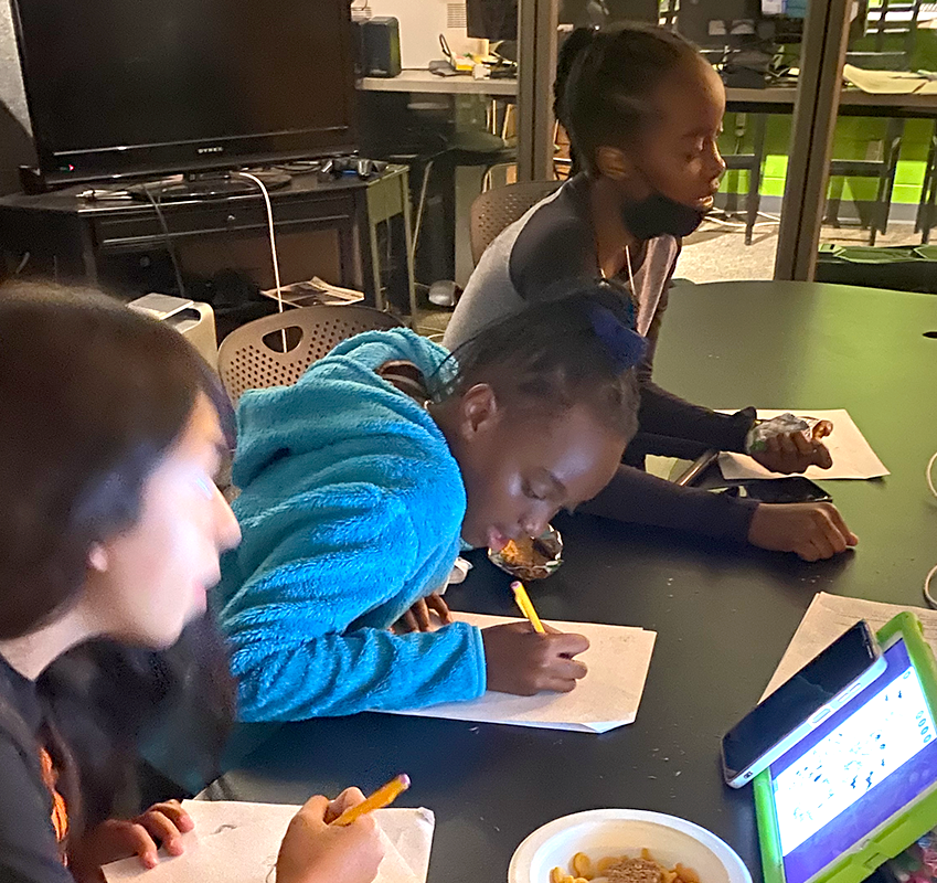 Three students at table taking notes